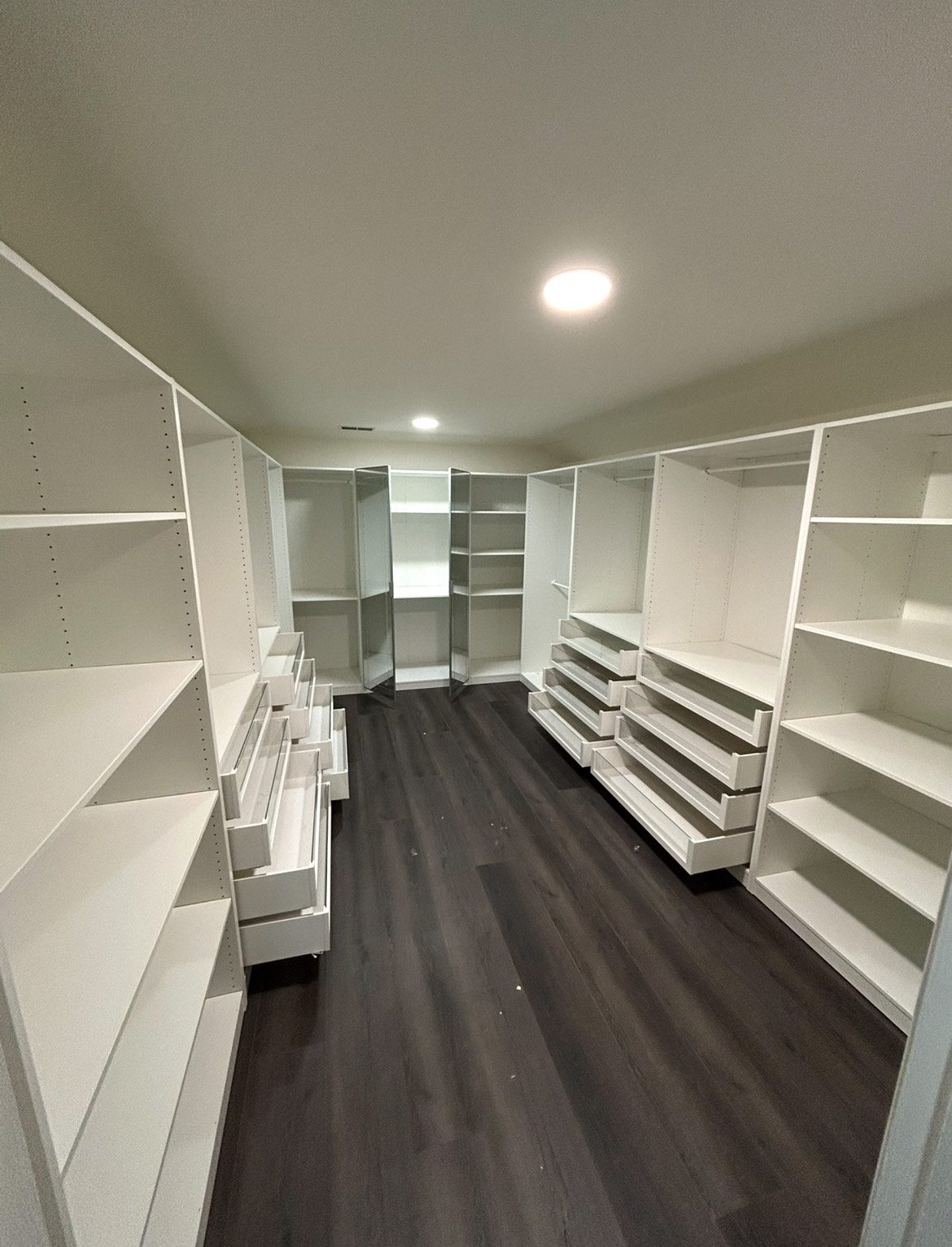 Empty walk-in closet with white shelves.